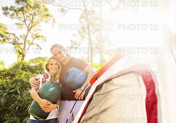 Portrait of smiling couple standing together next to tent
