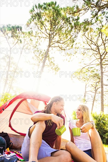 Couple sitting with coffee in front of tent