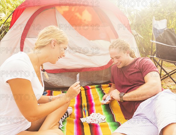 Couple playing cards in front of tent