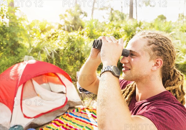 Young man watching birds through binoculars