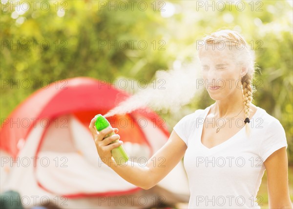 Woman spraying head with bug spray