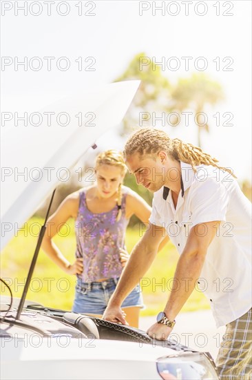 Couple checking car engine