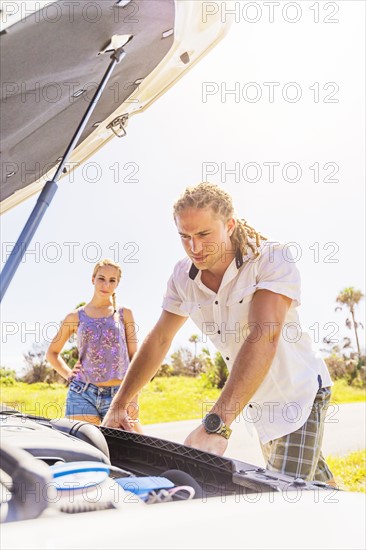 Couple checking car engine