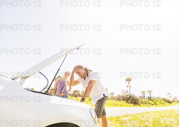 Couple checking car engine