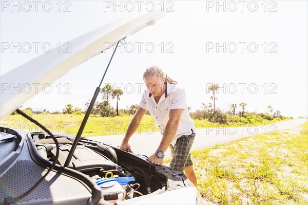 Young man looking at car engine