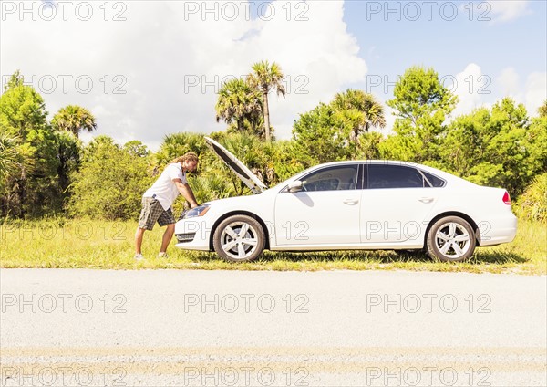 Young man looking at car engine