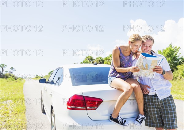 Couple at back of car looking at map
