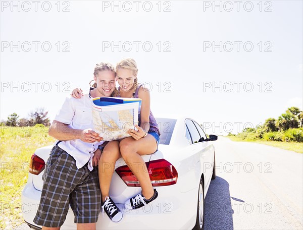 Couple at back of car looking at map