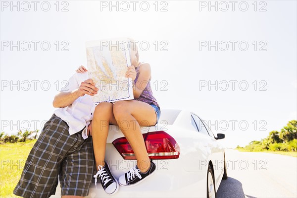 Couple at back of car looking at map