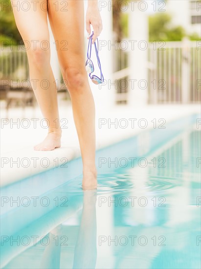 Woman checking water at swimming pool