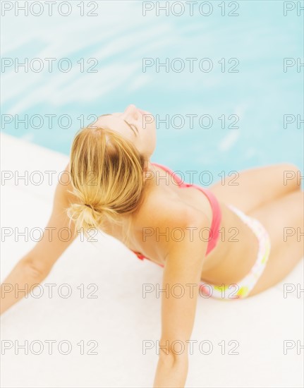 Woman sunbathing next to swimming pool