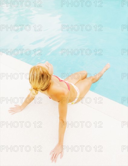 Woman sunbathing next to swimming pool