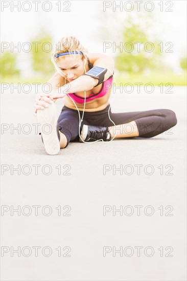 Young woman listening to music while stretching