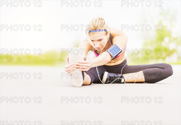 Young woman listening to music while stretching