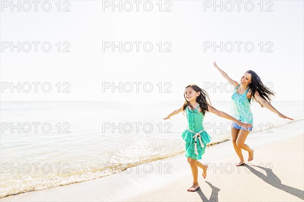 View of girl (6-7) and her mom running on beach