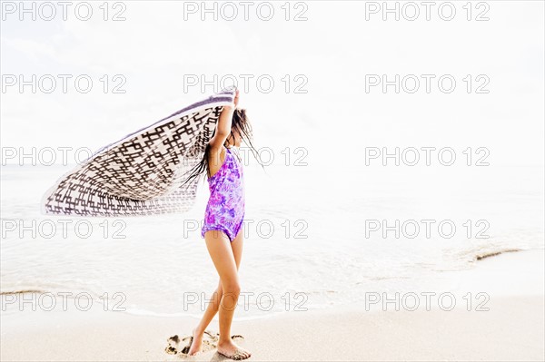 Girl (6-7) spinning on beach