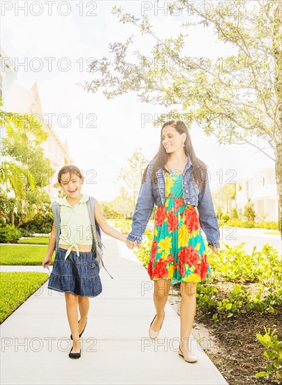 Girl (6-7) walking to school with her mom