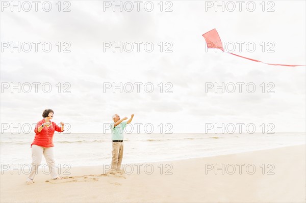 Couple flying kite together on beach