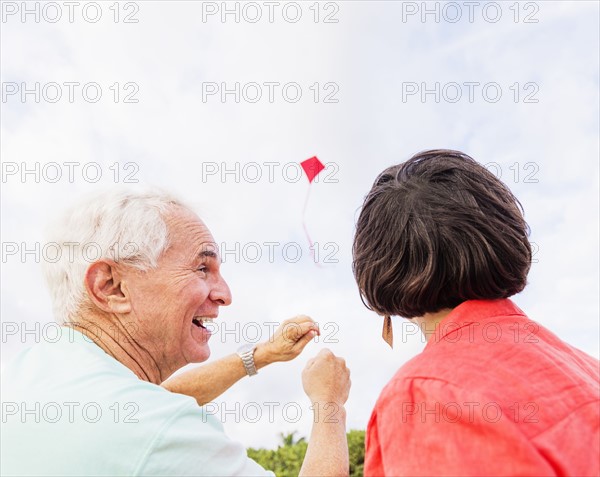 Low-angle view of couple flying kite together