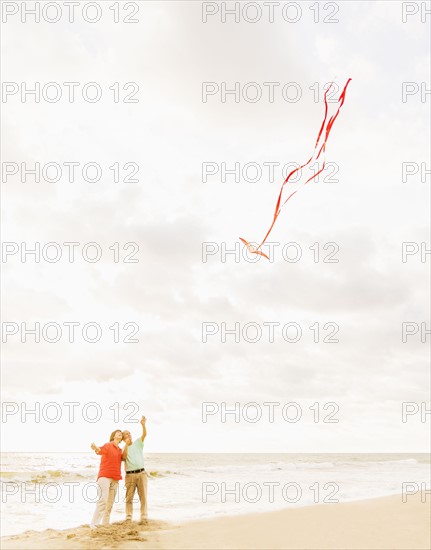 Couple flying kite together on beach