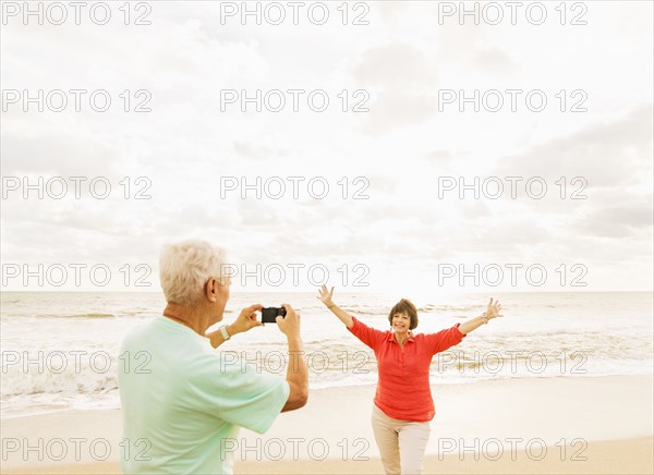 Couple taking pictures on beach at sunrise