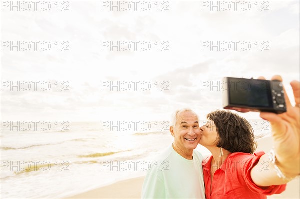 Couple taking selfie on beach at sunrise