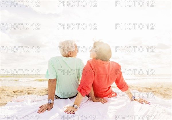 Rear view of couple looking at each other on beach at sunrise
