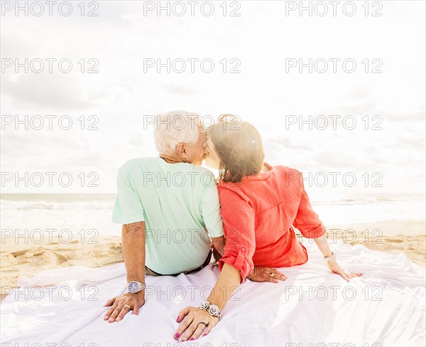Rear view of couple kissing on beach at sunrise