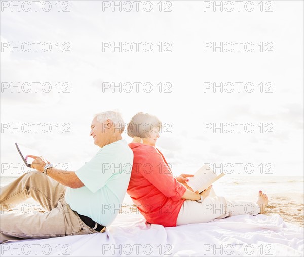 Couple sitting back to back on beach