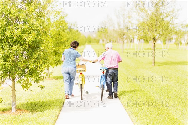 Rear view of couple wheeling bicycles along cycling path