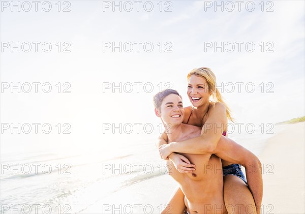 Boyfriend carrying girlfriend piggyback on beach