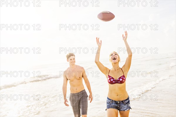 Young woman catching football on beach