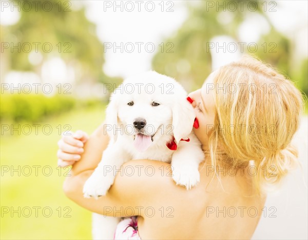 Close-up shot of young woman embracing white puppy