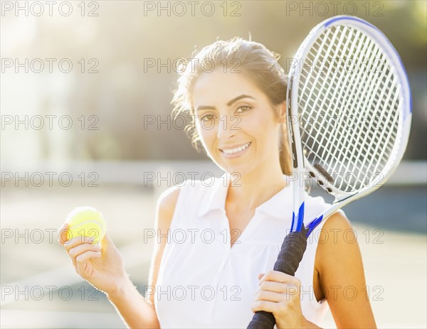Portrait of young woman holding tennis ball and tennis racket