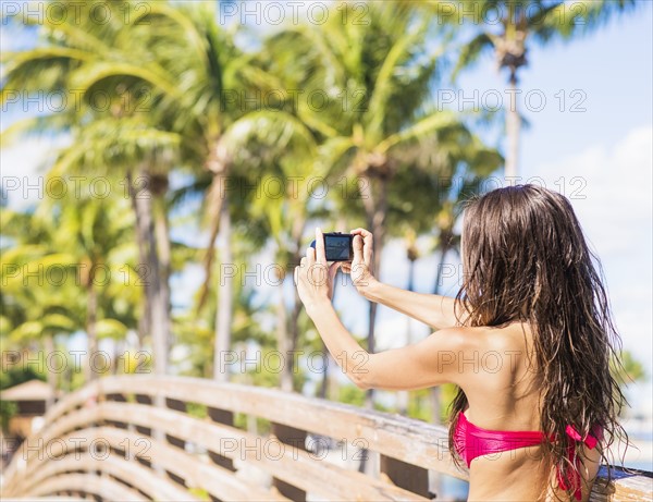 Young woman photographing wooden bridge