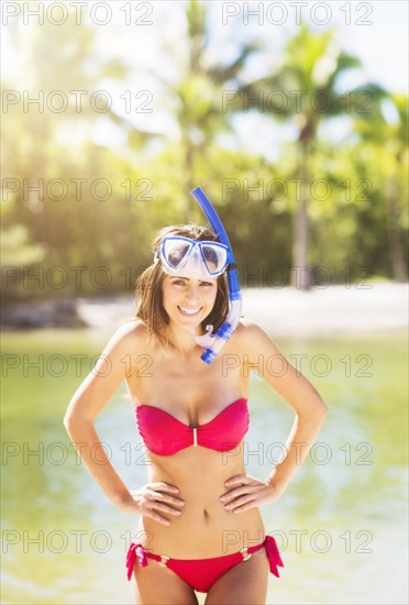 Portrait of young woman wearing bikini with snorkel and scuba mask on tropical beach