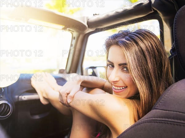 Portrait of young woman sitting in car with legs on dashboard