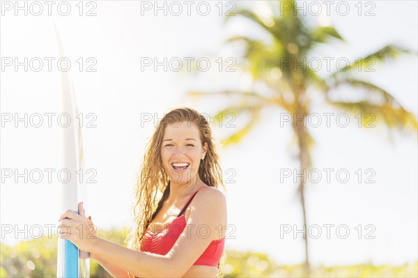 Portrait of young woman holding surfboard on beach