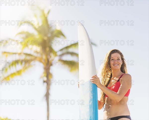 Portrait of young woman holding surfboard on beach