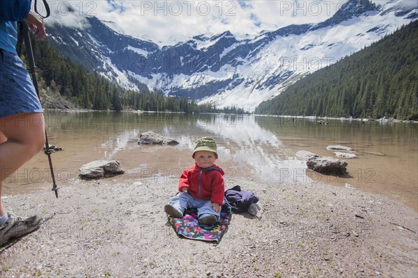 Boy (4-5) sitting on lakeshore