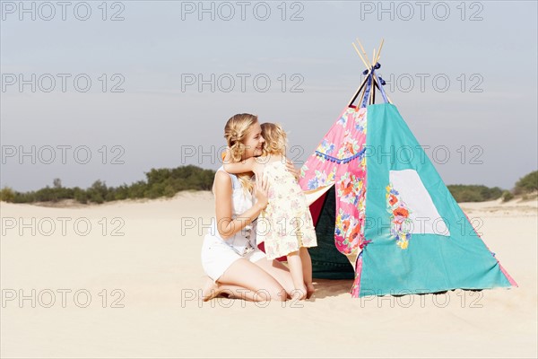Mother hugging daughter (2-3) on beach