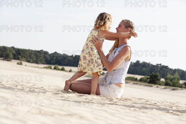 Mother playing with daughter (2-3) at sandy beach