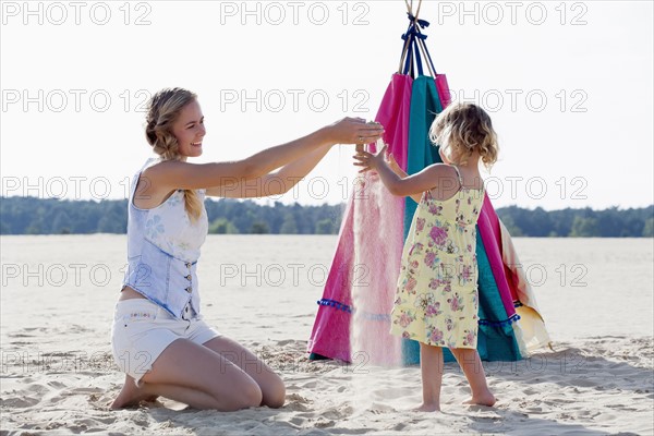 Mother playing with daughter (2-3) at sandy beach