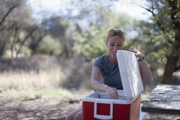 Smiling woman opening cooler in park
