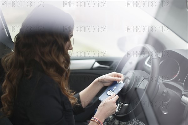 Young woman sitting in car and holding parking ticket