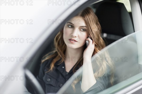 Young woman speaking on phone in car