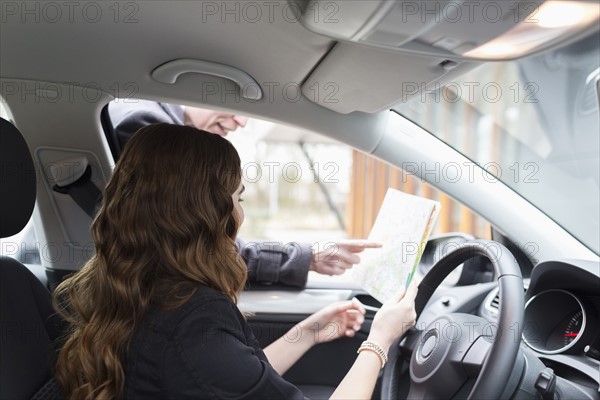 Man giving directions to young woman in car