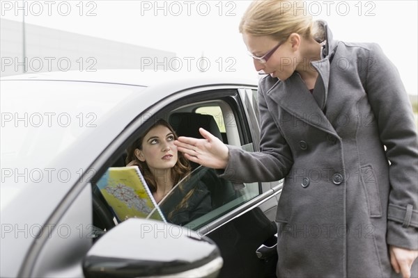 Woman giving directions to young woman in car