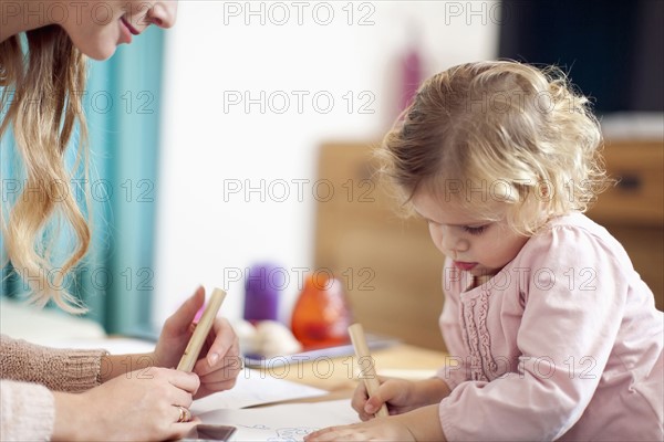 Woman teaching young girl (2-3) at home