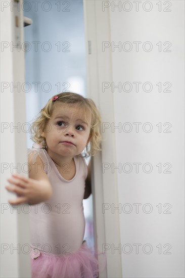 Girl (2-3) in pink skirt opening bedroom door